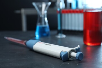 Laboratory analysis. Micropipette with liquid on black table, closeup