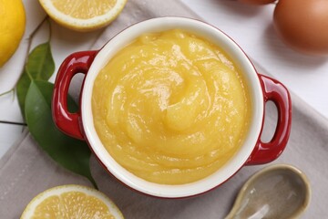 Delicious lemon curd in bowl, ingredients and spoon on table, flat lay