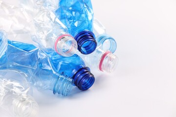 Crumpled disposable plastic bottles on white background, space for text