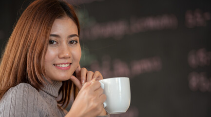 Banner of Asian woman Proprietor holding hot coffee in white ceramic cup to sniff smell of espresso...