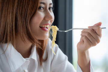 Woman in white clothes holding and smell white dish plate with pasta homemade spaghetti marinara in...