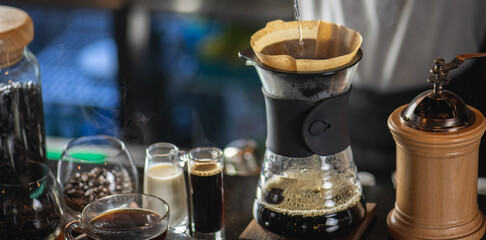 drip coffee, Barista making drip coffee by pouring spills hot water on coffee ground with prepare filter from copper pot to glass transparent chrome drip maker on wooden table in cafe shop