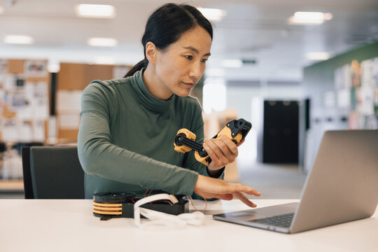 Woman using a laptop to programme a robotic arm