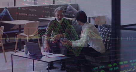Image of stock market data processing against two diverse men discussing over laptop at office
