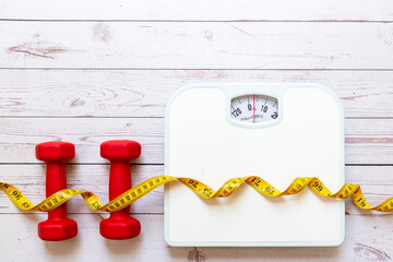 Weight loss control planning.  White scale and measuring tape with dumbbell for body dieting healthy life. Top view