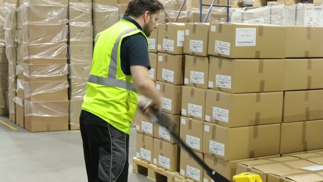 pallet truck forklift worker inside a factory warehouse moving package ready for shipping