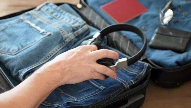 Man packing suitcase for travel vacation, close-up. Man hands putting clothes