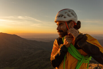 A man in a yellow jacket is adjusting his helmet. The scene is set in a mountainous area with a...