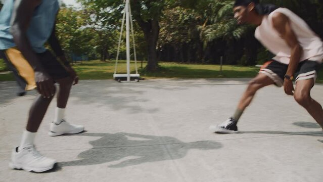 Handheld shot of two African American sportsmen having streetball game on outdoor court