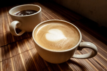 Two cups of coffee, Americano and cappuccino, in a cafe, an atmospheric photo of morning drinks
