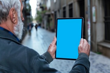 Ui mockup through a shoulder view of a mature man holding a tablet with an entirely blue screen