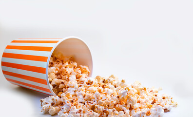 Popcorn spilling from orange bucket isolated on white background. 