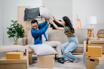 Young couple with big boxes moving into a new house, new apartment for couple, young asian man and woman helping to lift boxes on sofa . - obrazy, fototapety, plakaty