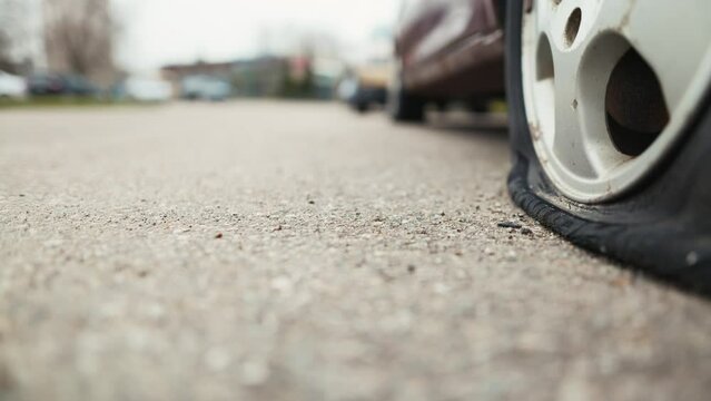 Witness the deterioration of an abandoned car with a flat tire in broad daylight, capturing every detail of its weathered appearance