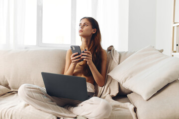 Smiling woman working on laptop in cozy living room, surrounded by modern devices and enjoying her freelance job online