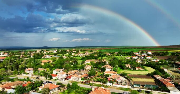 Bulgarian village in the countryside and beautiful bulgarian nature and agricultural fields , aerial panorama view with rainbow in sky