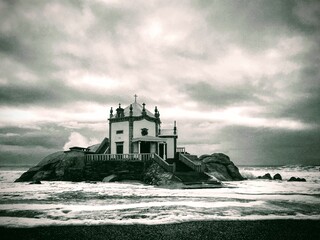Senhor da Pedra chapel on the Atlantic Ocean coast against the stormy sky near Porto, Portugal,...