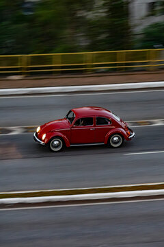 Red Volkswagen Bettle cruising highway, Panning shot of a vintage german car