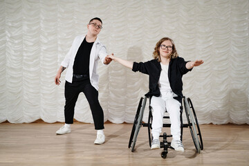 Long shot of young Caucasian man and woman with disability in wheelchair performing modern dance on stage, copy space