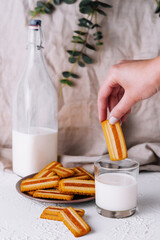 Hand dipping biscuit into milk glass