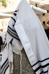 A tallit or Jewish prayer shawl draped over the silver case enclosing a Sefardi style Torah scroll.