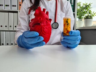 Cardiologist doctor with red heart and pills in hospital