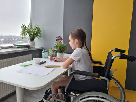 Young Girl Sitting in Wheelchair at Desk