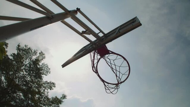 Low angle shot of streetball hoop and thrown by players ball on sunny day outdoors, no people