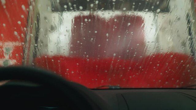 Car getting cleaned with water and liquid in car wash