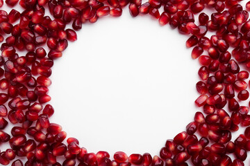 Frame made of ripe juicy pomegranate grains on white background, top view. Space for text