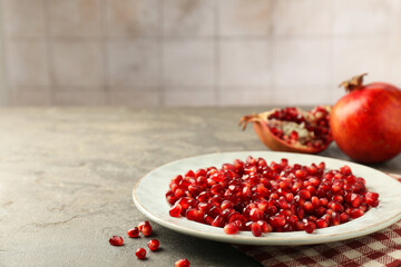 Tasty ripe pomegranate grains on grey table. Space for text