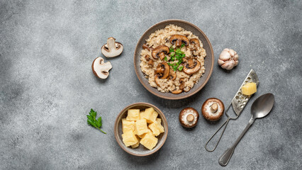 Risotto with brown champignons on a gray rustic background. Italian food. Top view, copy space. Banner.