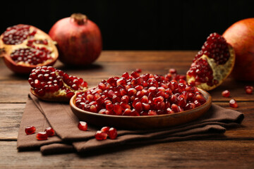 Ripe juicy pomegranates and grains on wooden table