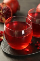 Tasty pomegranate juice in glasses on grey table, closeup