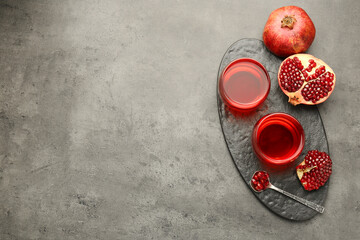 Tasty pomegranate juice in glasses and fresh fruit on grey table, top view. Space for text