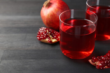 Tasty pomegranate juice in glasses and fresh fruits on black wooden table, closeup. Space for text