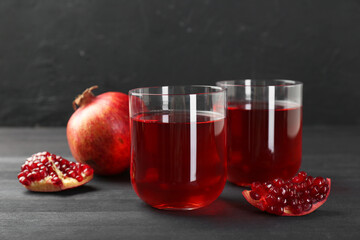 Tasty pomegranate juice in glasses and fresh fruits on black wooden table
