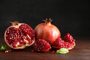 Fresh pomegranates and green leaves on wooden table