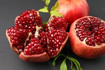 Fresh ripe pomegranates and leaves on grey background, closeup