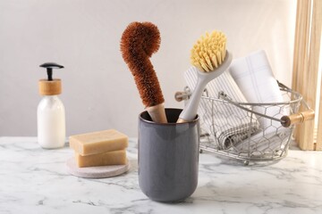 Brushes in holder and cleaning tools on white marble table
