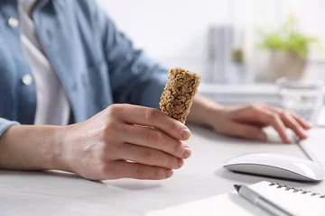 Badkamer foto achterwand Woman holding tasty granola bar at light table in office, closeup © New Africa