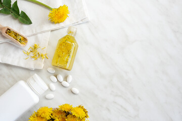 Bottle of essential oil of dandelions on marble background. Medicinal plants and herbs composition. Healthy nutrition concept. Closeup. Flat lay, top view, place for text.