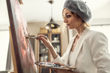 Beautiful female painter enjoying while painting in home art studio. Woman Artist Works on Abstract acrylic painting in the art studio