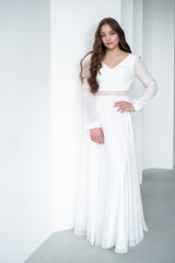 portrait of beautiful young woman in white wedding dress posing in studio.