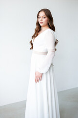 portrait of beautiful young woman in white wedding dress posing in studio.