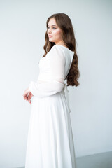 portrait of beautiful young woman in white wedding dress posing in studio.