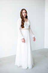 portrait of beautiful young woman in white wedding dress posing in studio.
