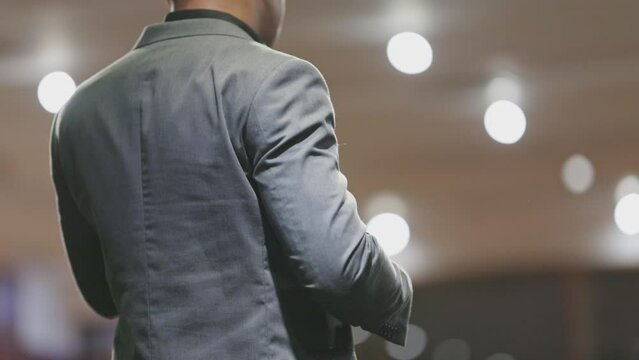A man is a lector - stands in front of a microphone - rear view