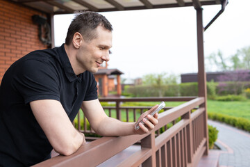 A young man using a mobile phone on the terrace of a house