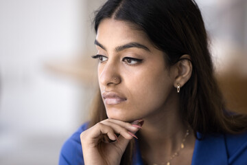 Sad pensive young Indian woman casual close up facial portrait. Concerned thoughtful 20s girl with nose stud touching chin, looking away, thinking on problems, bad news